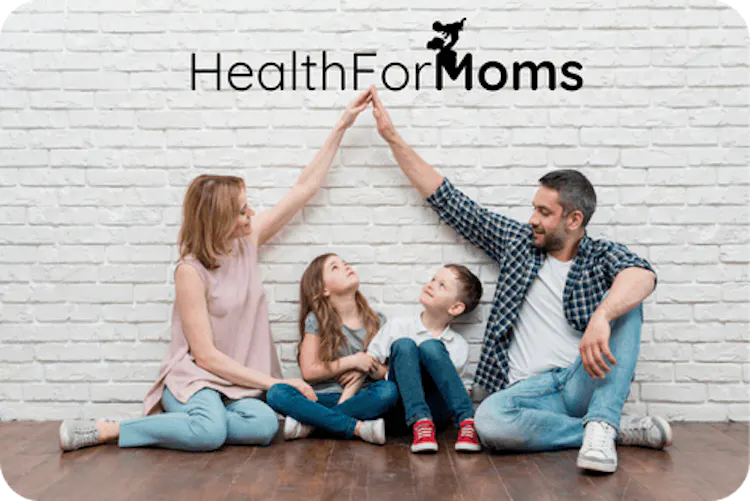 A family of four sitting on the floor against a white brick wall, parents giving a high five above two children looking up at them, with "HealthForMoms" text on the wall.